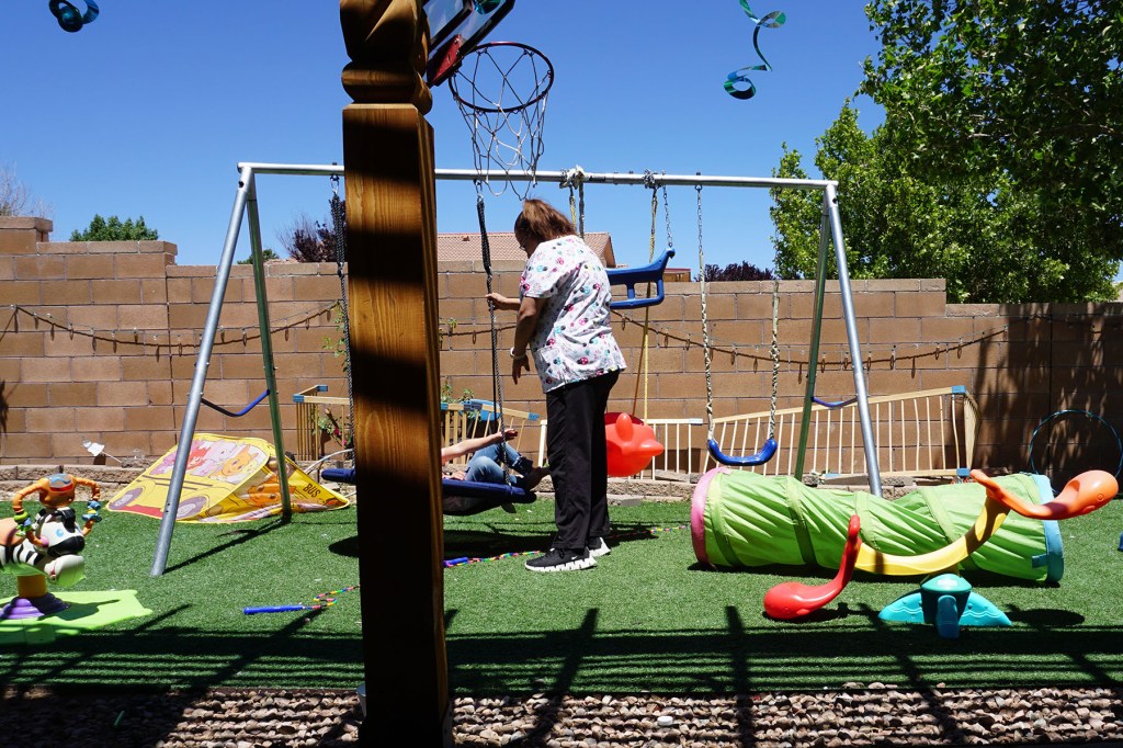 Maggi plays with a child in the back yard of her child care program.