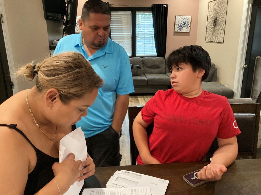 Antonio Arellano (center) watches as his wife, Abigail, and son, 11-year-old Samuel, go through the many medical bills the family received after Samuel was shot at the Kansas City Chiefs Super Bowl parade on Feb. 14, 2024.