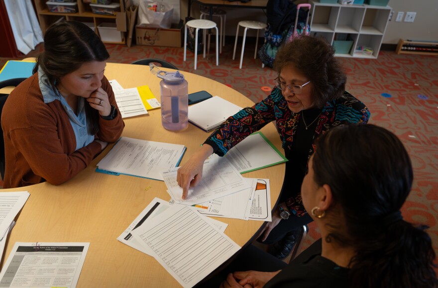 A woman discusses something on a paper with two other women.