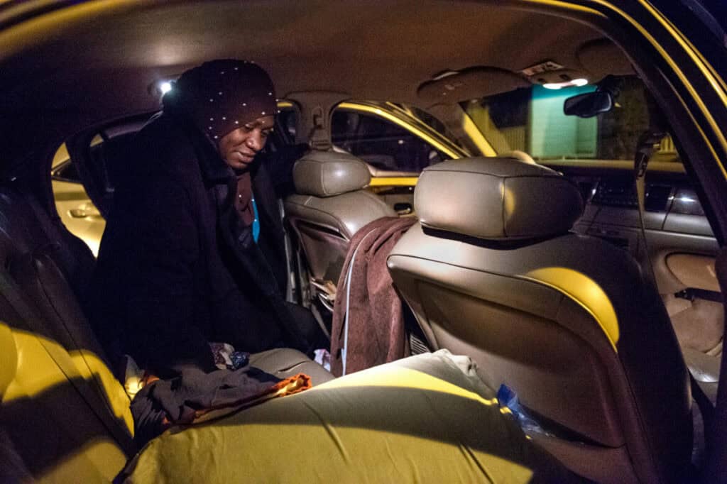 Personal care assistant resting inside a car after long work hours.