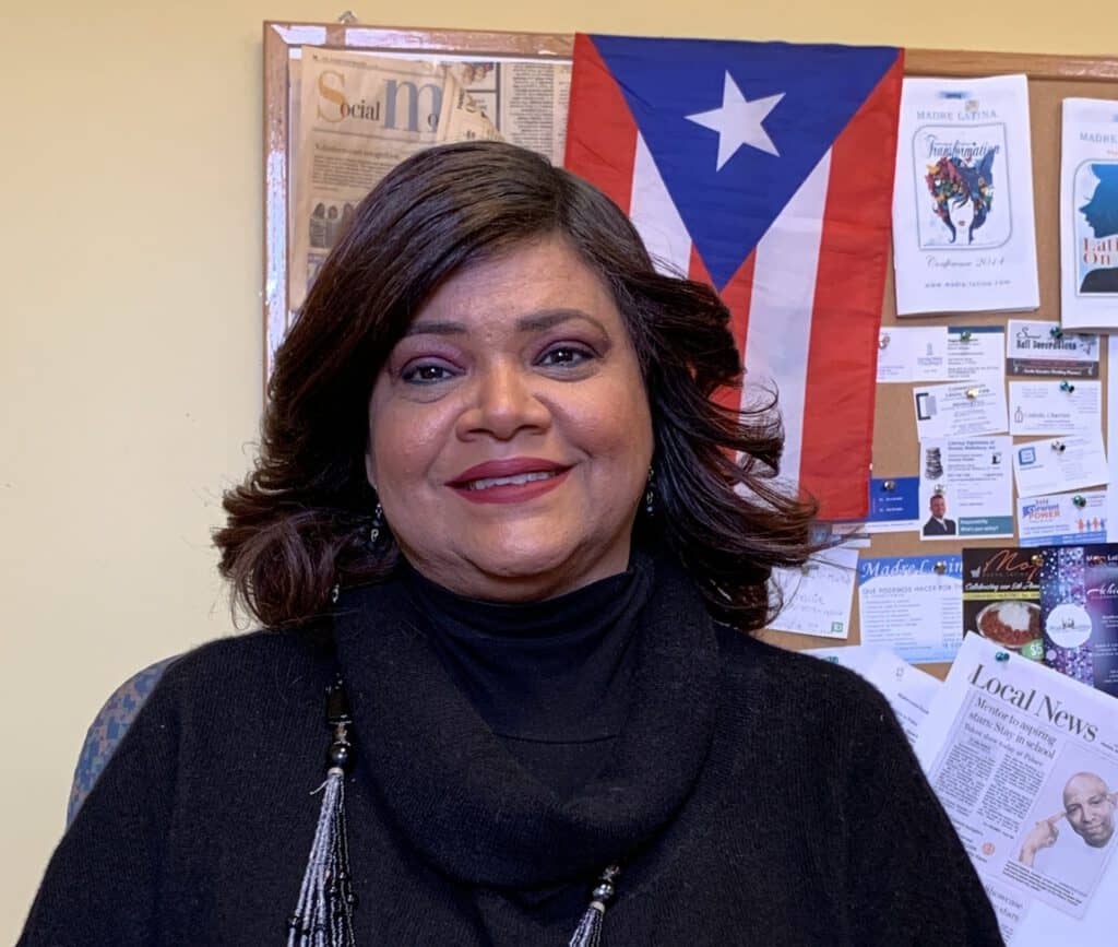 Puerto Rican woman smiling, Puerto Rico flag in background, celebrating cultural pride and motherhoo.