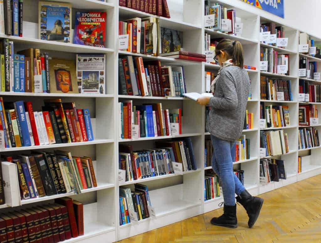 Student browsing books in a library promoting Latino college enrollment and familismo values.