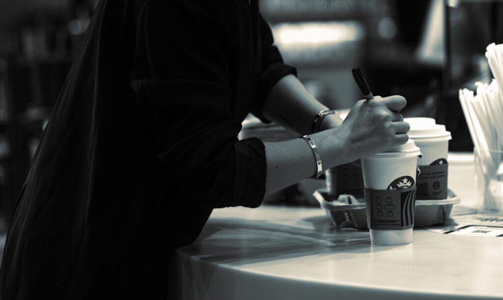 Relaxed woman writing on a coffee cup at a modern workspace.