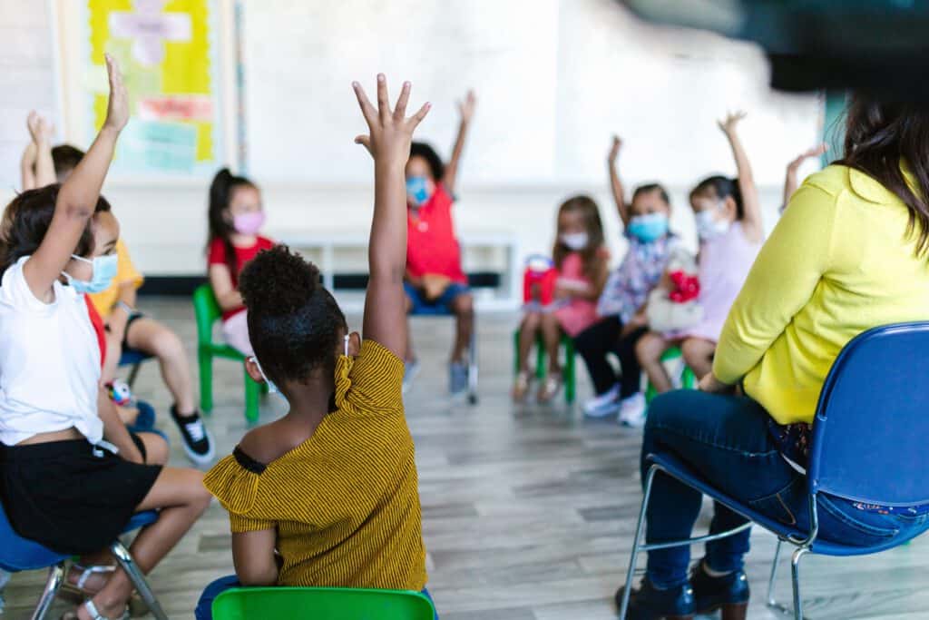 Bilingual classroom with students raising hands during lesson in Illinois.