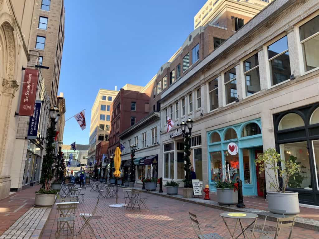 Downtown city street with outdoor cafes and historic buildings, sunny day.