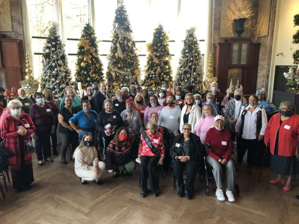 Celebration with diverse children and elderly at community holiday event in front of decorated Chris.