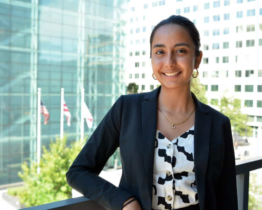 Young Latina student advocating for domestic worker rights outdoors.