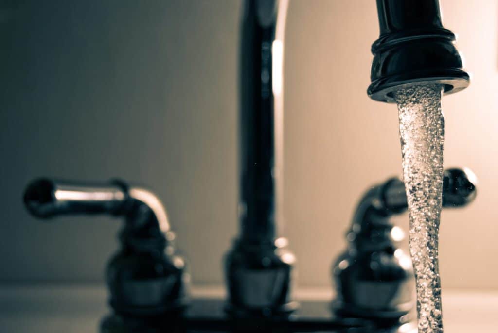 Tap water flowing from a faucet, highlighting concerns about lead contamination in municipal drinkin.