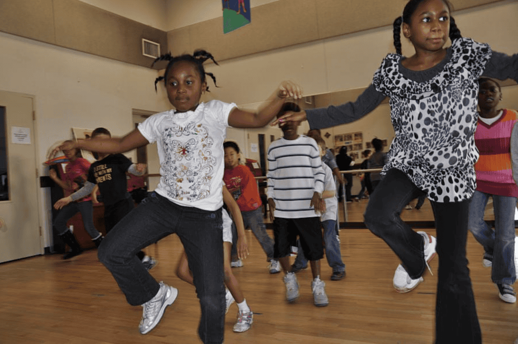 Outdoor children dancing in a community center promoting active recreation.