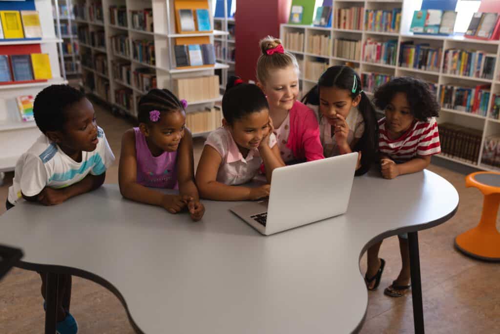 Children using a laptop in a library for digital learning and inclusion.