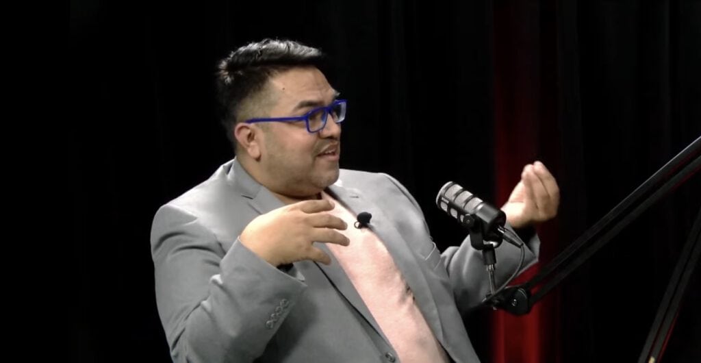 A man speaking into a microphone during a presentation or interview.