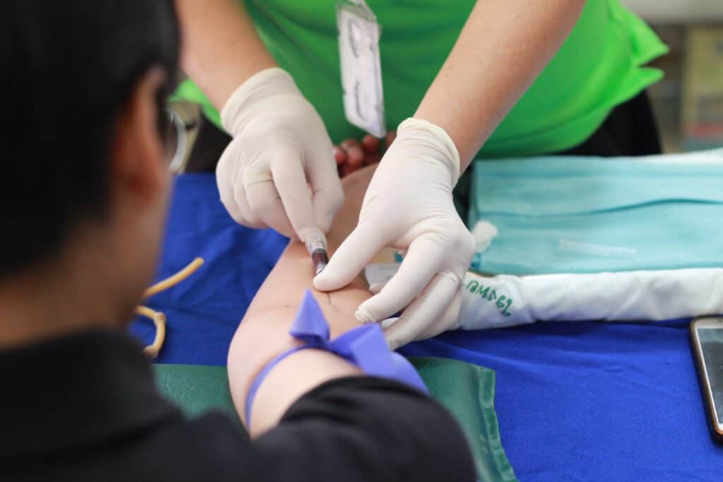 Blood donation process with healthcare professional preparing to draw blood from a donor.