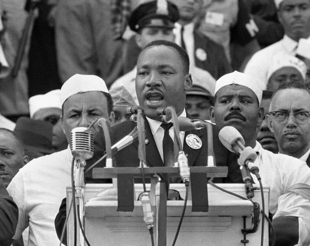 Martin Luther King Jr. speaking at a rally with diverse supporters, highlighting unity between the A.