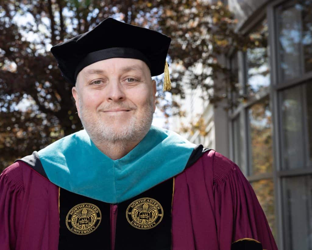 Academic graduate wearing cap and gown celebrating diversity in education outdoors.