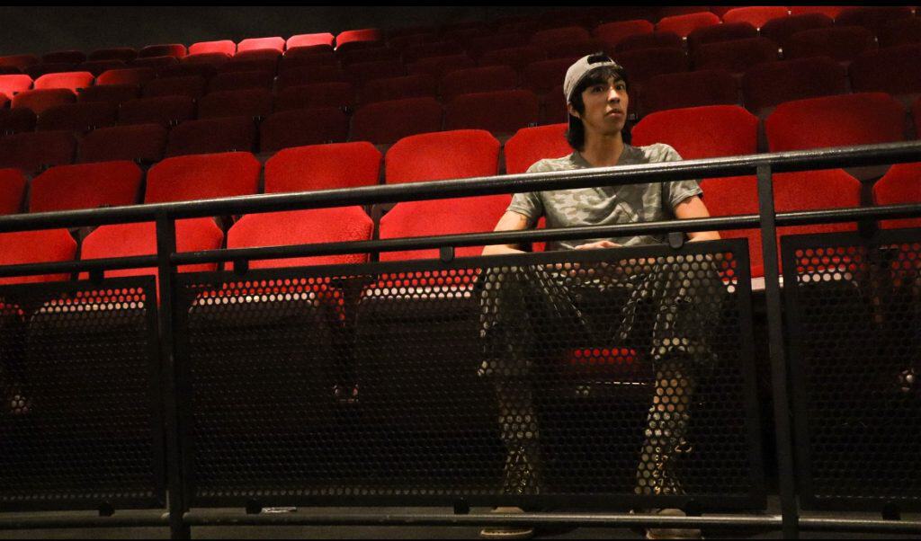 Young person sitting alone in an empty theater, exploring sound and music.