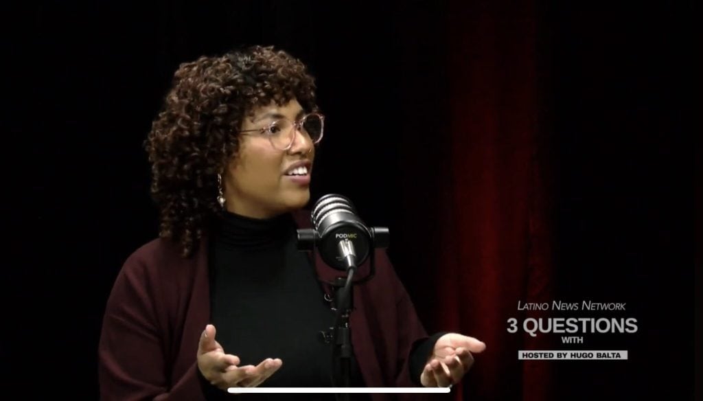 A woman speaking passionately at a microphone during a discussion on Latinidad.