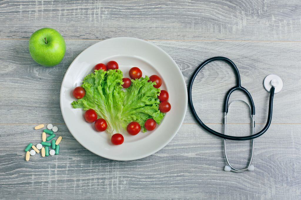 Fresh green apple, cherry tomatoes, and a stethoscope on a wooden surface, highlighting health and n.