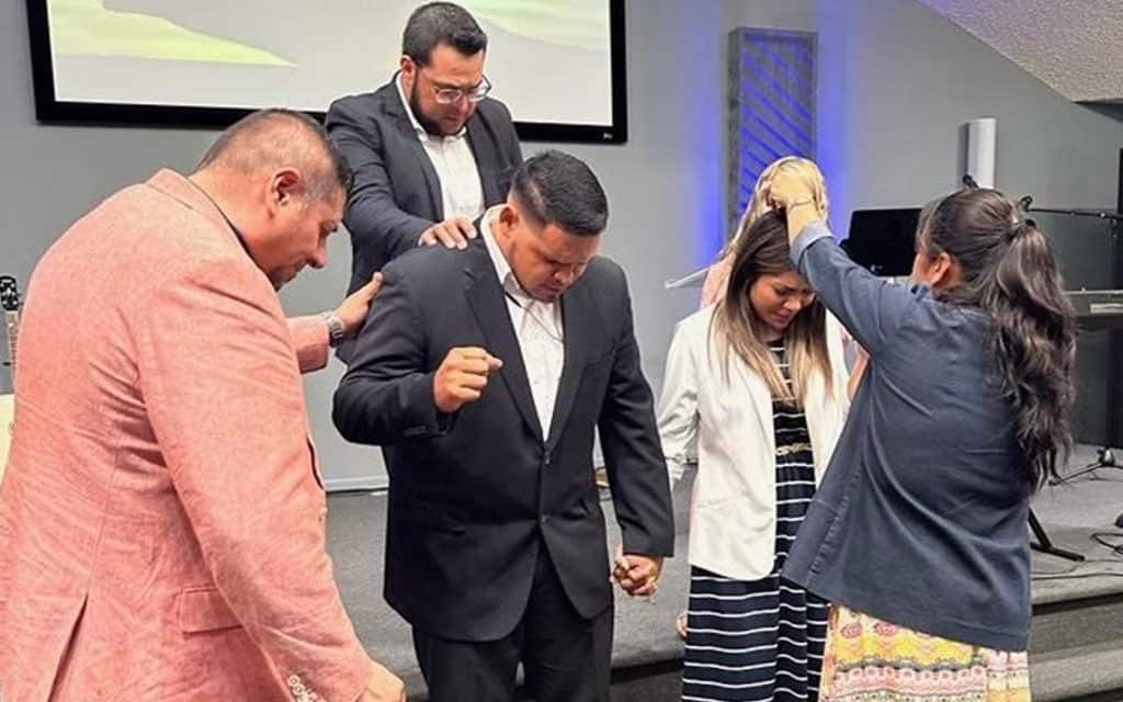 Bilingual church congregation praying and worshiping in Bowman community center.