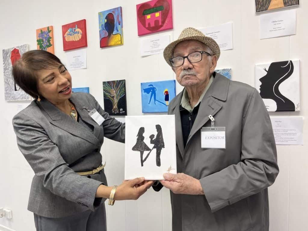 Senior man with dementia holding artwork at art exhibition.