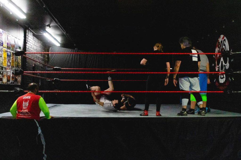 High-energy lucha libre match featuring Mexican wrestlers in a wrestling ring with red ropes.