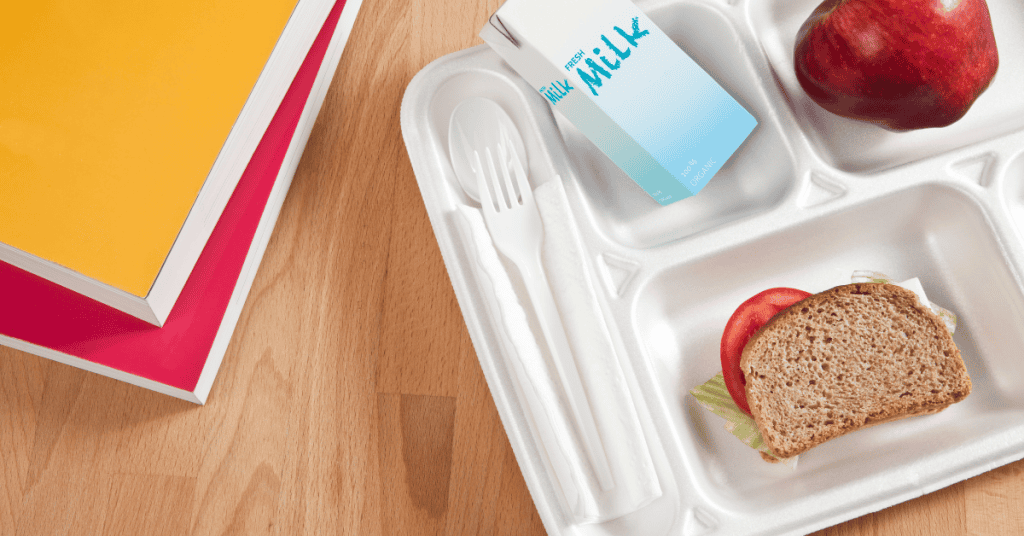 School lunch tray with milk, apple, and sandwich promoting child nutrition programs.
