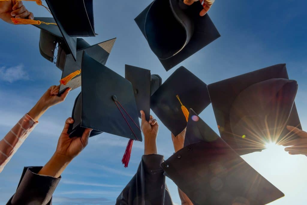 Graduates celebrating with caps in the air during a graduation ceremony.