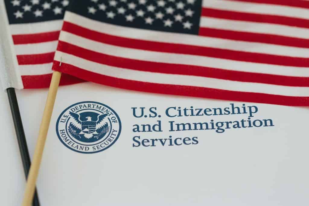 U.S. Citizenship and Immigration Services document with American flag in background.