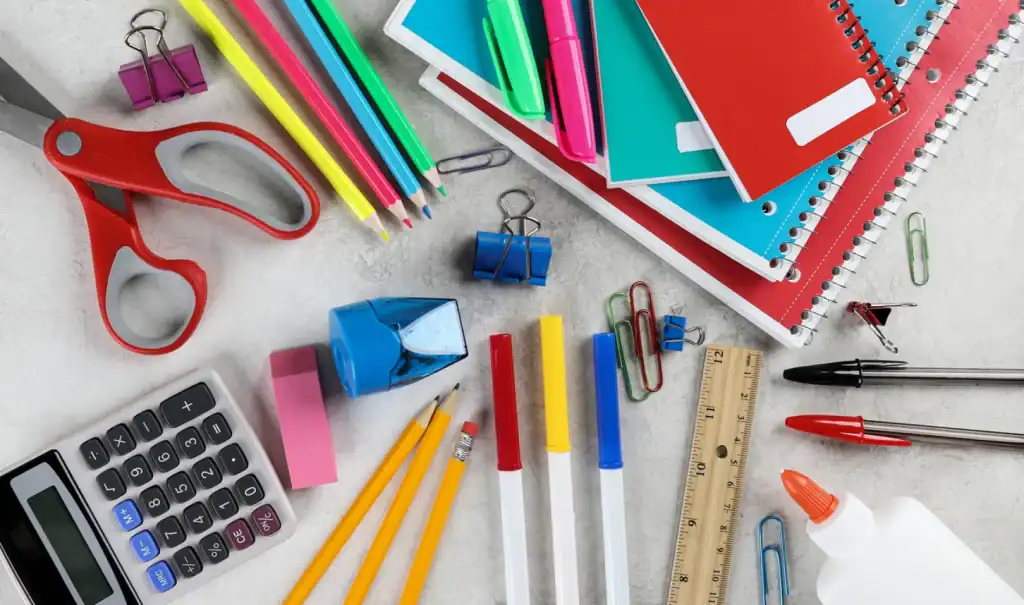 Colorful school supplies including notebooks, pens, scissors, and paper clips arranged on a desk.