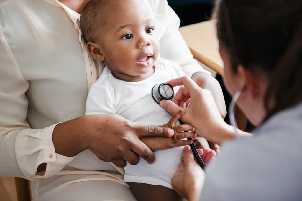 Uninsured child receiving medical checkup from healthcare professional in a clinic setting.