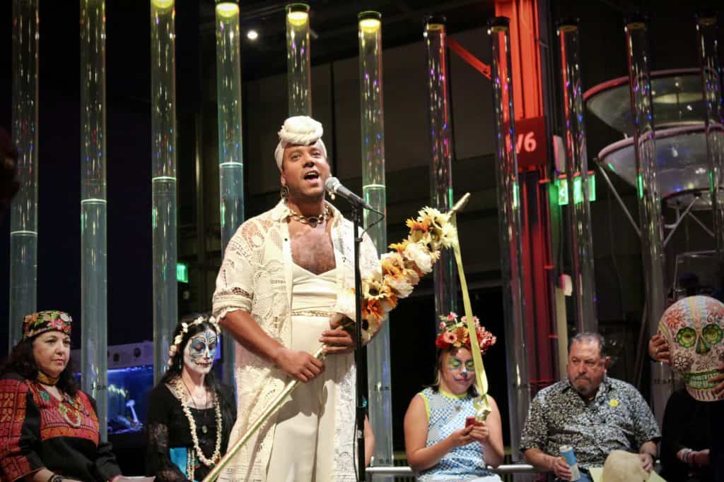Performer singing at a cultural event with traditional costumes and face paint.