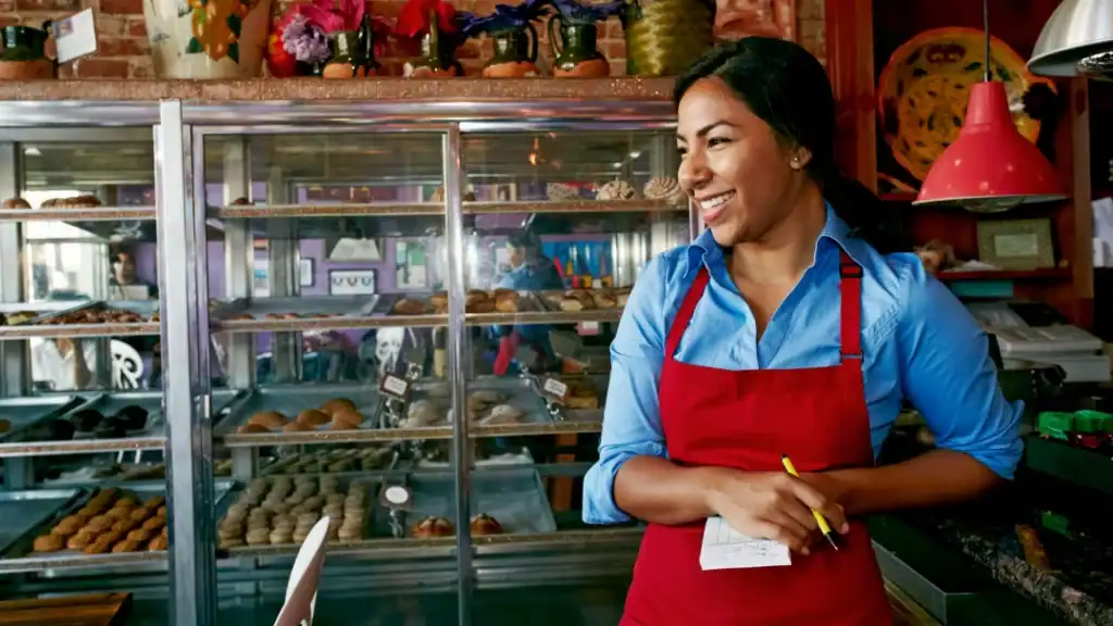Latina baker smiling in her bakery shop, showcasing Hispanic women’s contributions to U.S. economy.