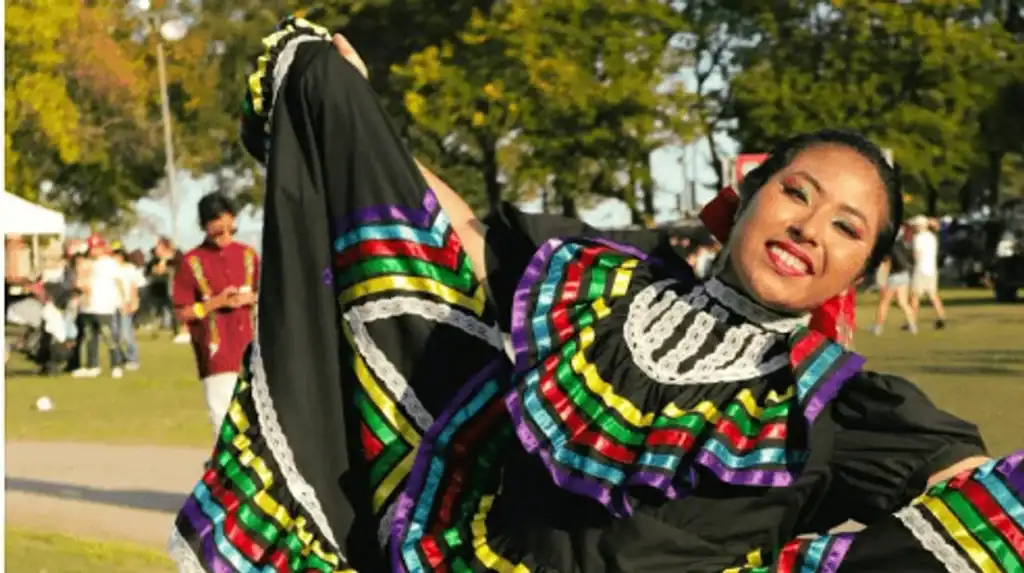 Joyful Latina dancer in traditional attire at cultural event.