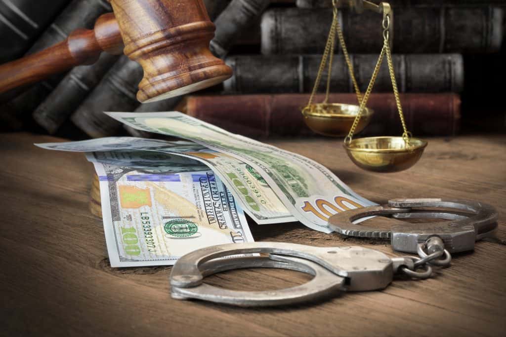Justice and financial bail system with money, handcuffs, and scales of justice.