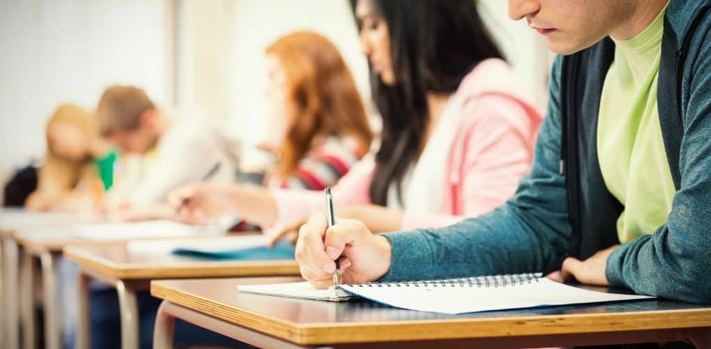 Students taking notes in a classroom to address education challenges in New York.