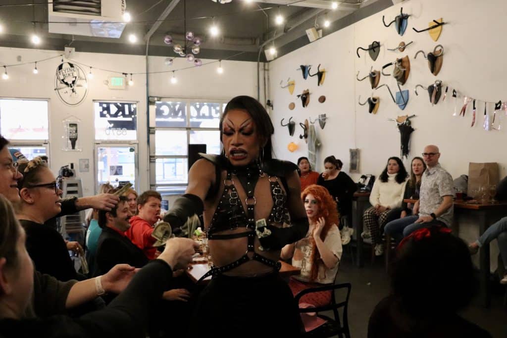 A woman performing a drag show at a lively indoor venue with an audience.