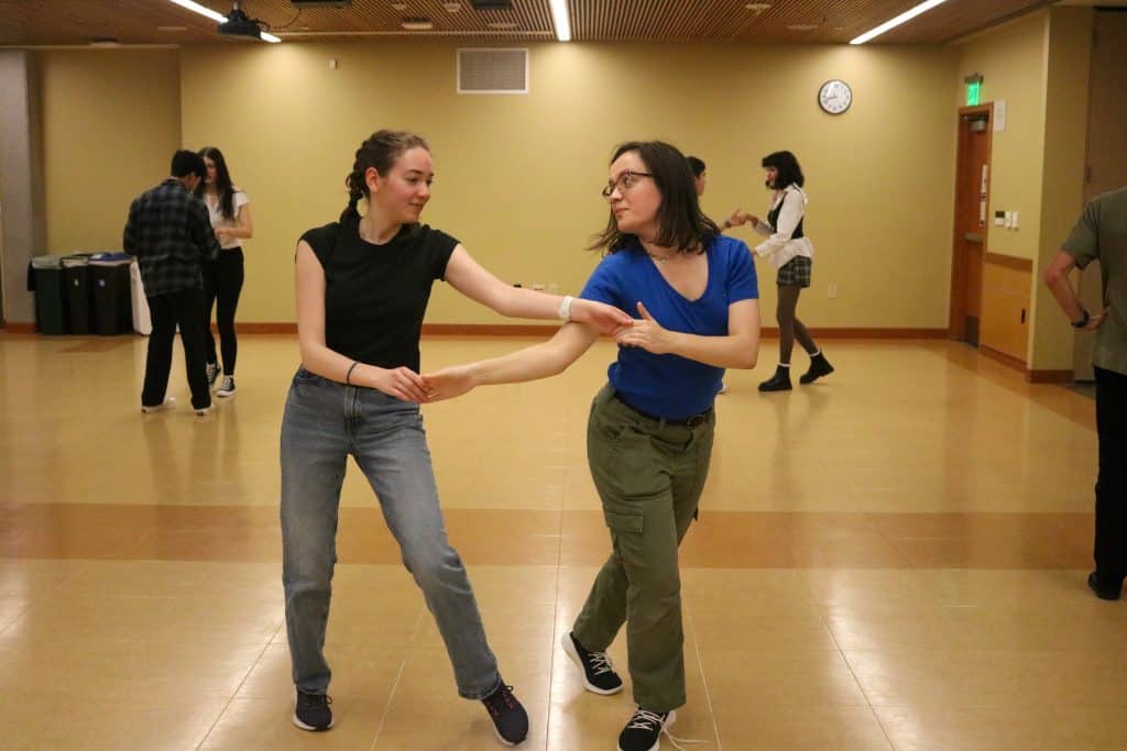 Dancing women practicing salsa in a community center for Latino cultural event.