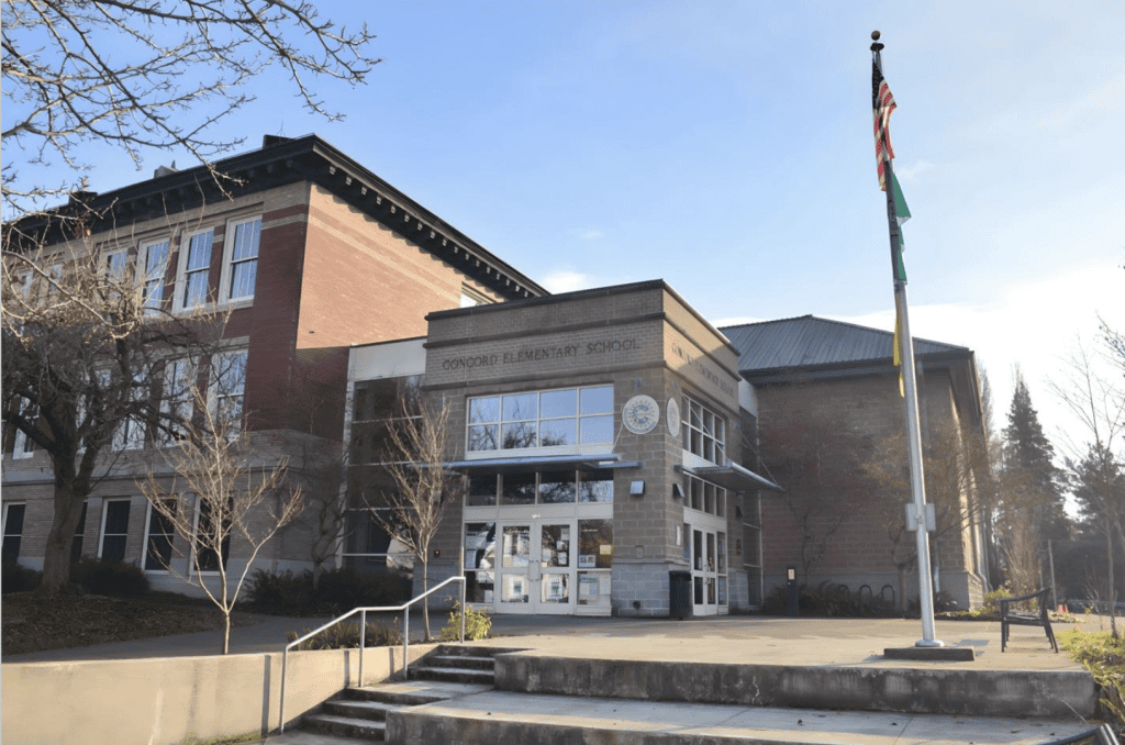 Bright exterior view of Concord Elementary School with American and state flags in front.