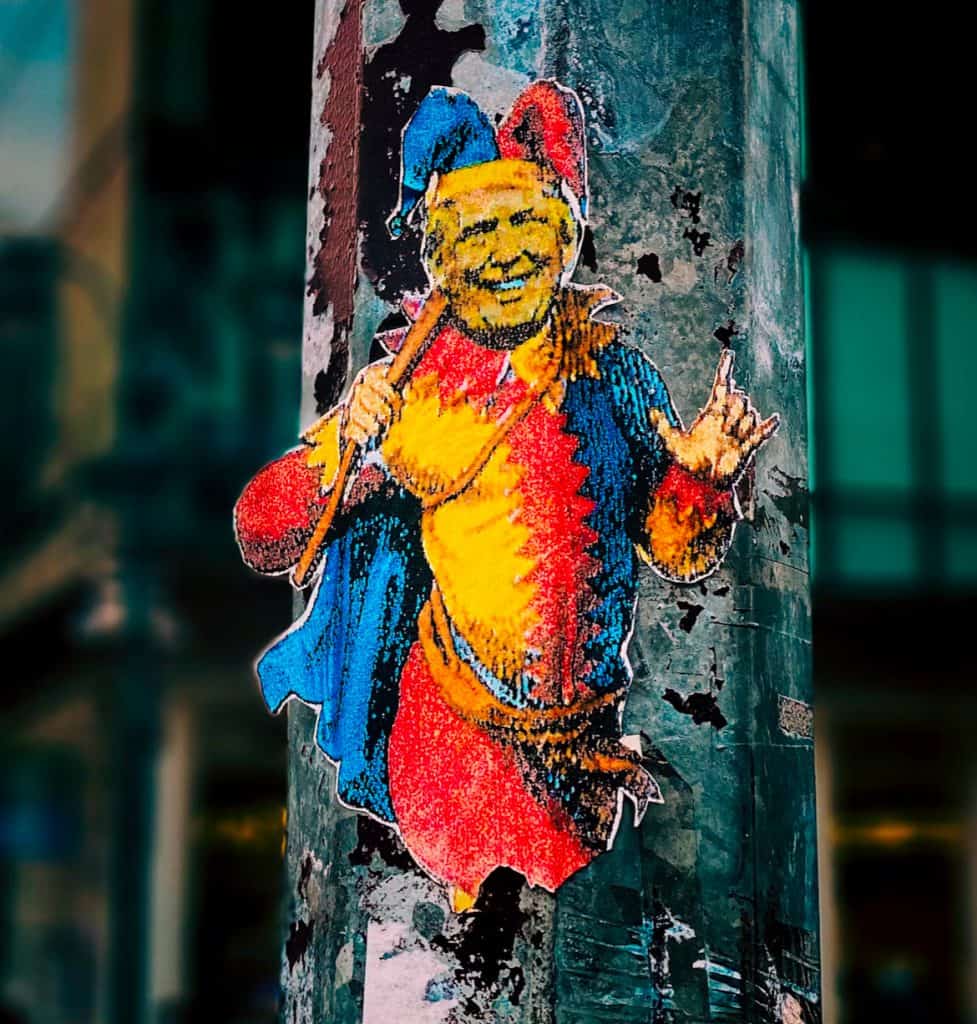 Colorful graffiti of a smiling clown on a pole, vibrant street art in an urban setting.