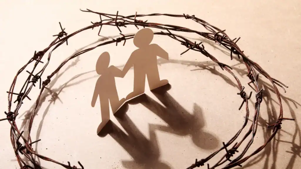 Paper cutout of two people holding hands inside barbed wire circle, symbolizing immigrant rights.