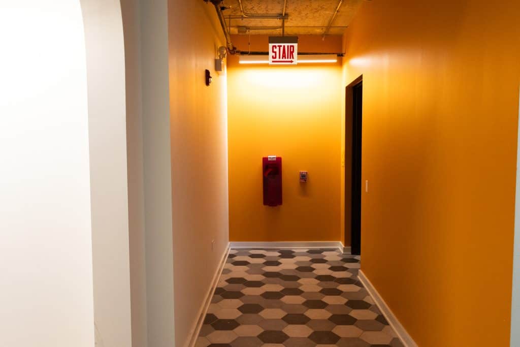 Hallway with yellow walls and hexagonal tile flooring, highlighting urban renewal efforts.