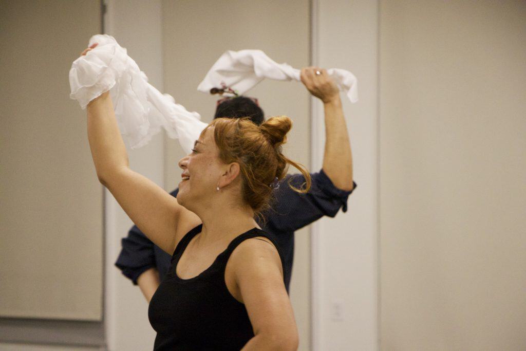 A woman dancing joyfully with a white cloth in her hand at a cultural event.