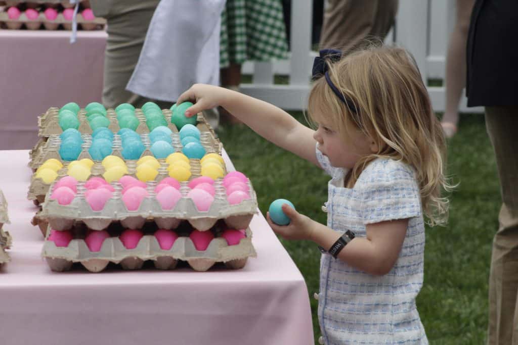 A girl reaching for an Easter egg at a White House egg roll event.