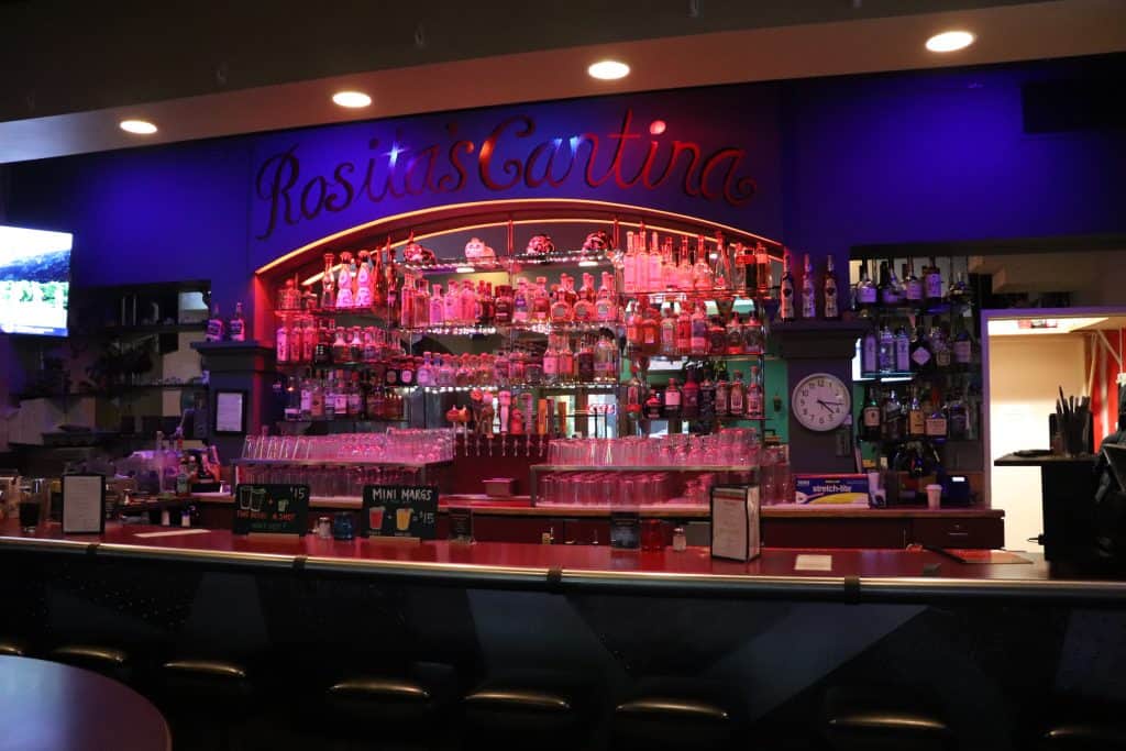Pink-lit bar with bottles and glasses at Rosita Cantina, a vibrant Latin-inspired restaurant and nig.