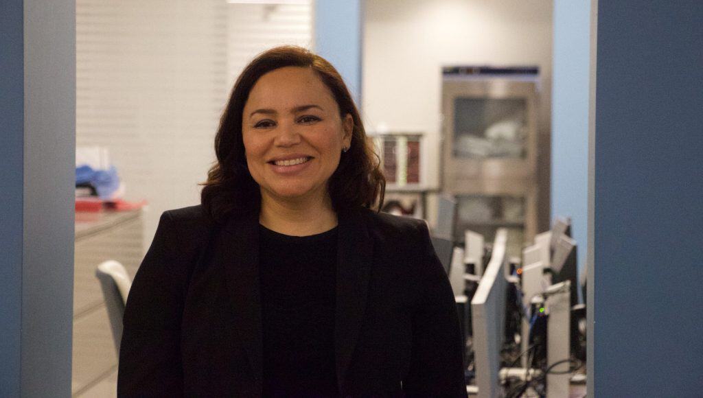 Bright Latina woman smiling in an office setting, representing purposeful design and professional su.
