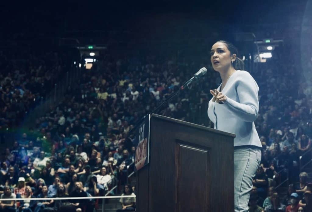 Democratic woman speaker at a rally addressing a large crowd, emphasizing middle-ground leadership.