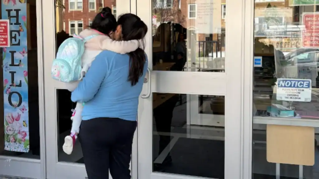 A woman and child entering a building with a "The Latino" sign on the door, indicating a community o.