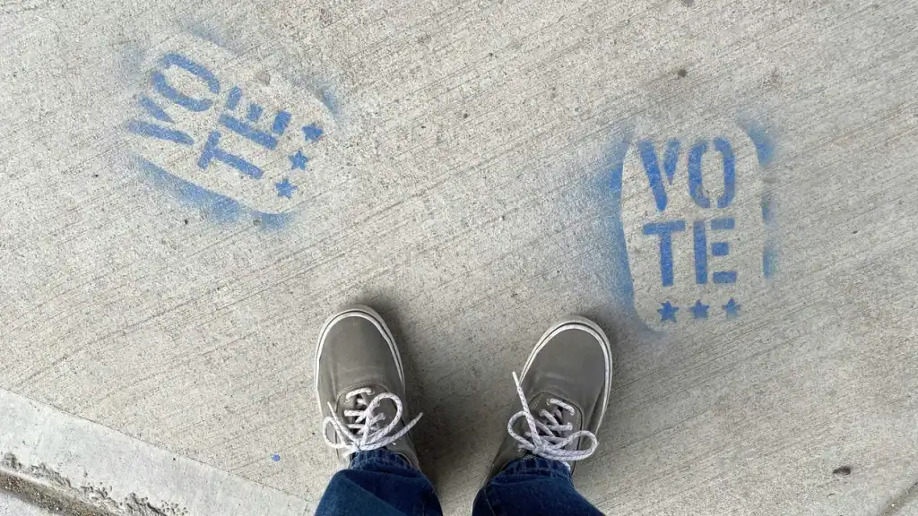 Voters' shoes on the ground with "Vote" and "Yes" stencils in New Mexico.