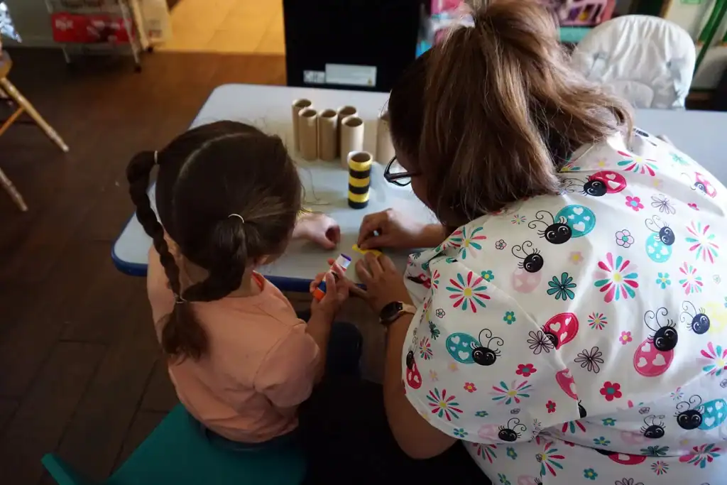 Child and caregiver working together on a learning project in a childcare environment.