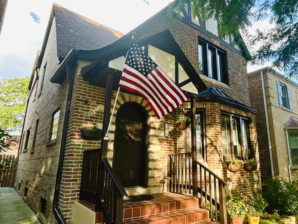 American flag displayed on a brick house during daytime.