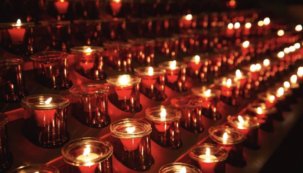 A candlelit vigil with numerous red candles symbolizing faith and remembrance.
